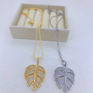 Macro view of Monstera leaf pendant necklace featuring sparkling zircon inlay details
