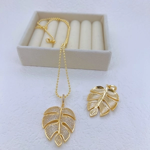 Elegant gold-plated monstera leaf necklace with sparkling cubic zirconia on white velvet