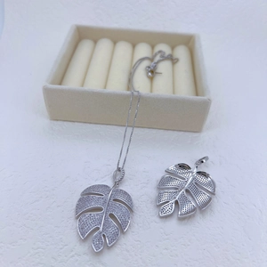 Silver monstera leaf pendant necklace featuring sparkling zircon stones on jewelry box