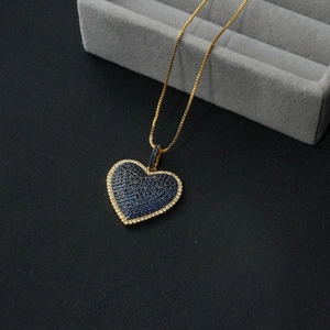 Detail of heart pendant with deep blue and white stones on a golden chain necklace