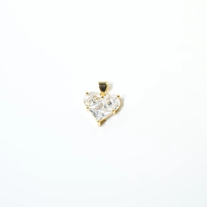 Macro d'un pendentif cœur plaqué or avec trois pierres en zircone cubique transparente