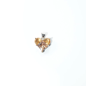 Detail of heart-shaped pendant with orange faceted gemstone and silver claw setting