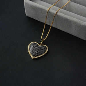 Detail of a heart pendant necklace featuring black pavé stones and gold box chain