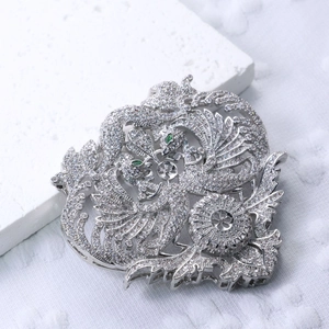 Macro detail of silver phoenix brooch with white cubic zirconia and green gemstones