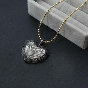 Nahaufnahme von Herzanhänger mit Zirkon-Pavé in Schwarz-Weiß an goldener Kugelkette