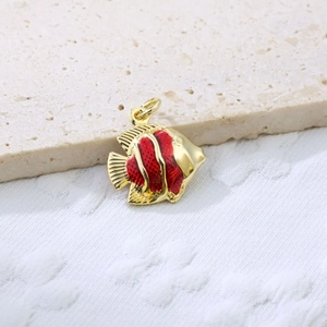 Close-up of tropical fish pendant featuring red enamel inlay and golden copper finish