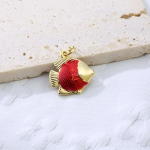 Macro shot of tropical fish pendant in gold copper with red enamel scales and loop