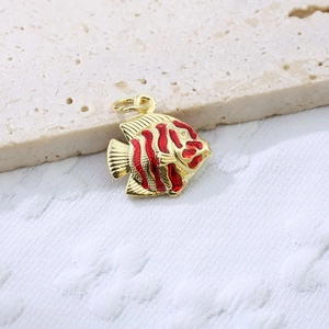 Macro shot of tropical fish pendant in gold metal with red enamel stripes detailing