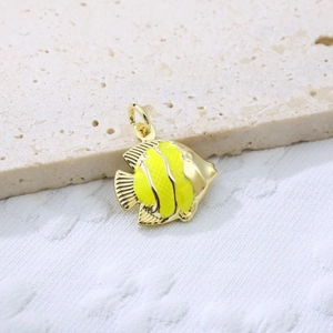 Macro view of gold-plated fish pendant with bright yellow enamel on textured background