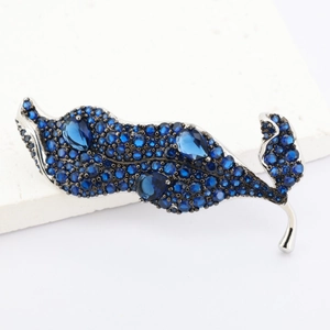 Broche feuille argentée élégante avec zircons bleu foncé sur un support en marbre