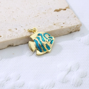 Detailed close-up of a gold-plated fish pendant with bright blue enamel on stone background