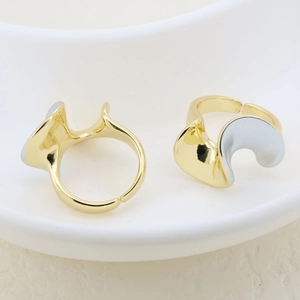 Detailed view of minimalist gold and silver wavy adjustable open rings on a ceramic plate