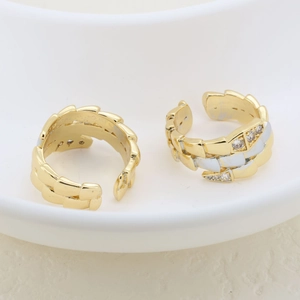 Detailed macro view of gold and silver plated rings with cubic zirconia on white ceramic