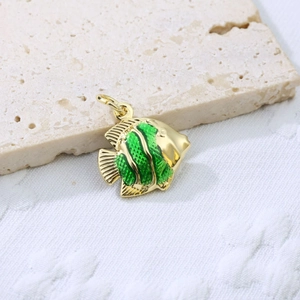 Detailed close-up of a golden fish pendant with green enamel on a stone surface
