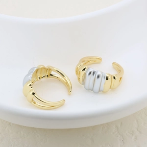 Two-tone adjustable open ring with vertical ribbed texture on a white ceramic plate