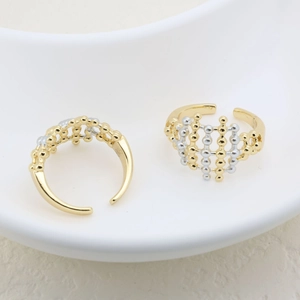 Macro detail of two-tone geometric mesh rings in gold and silver finish on white tray