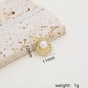 Vue macro du pendentif coquillage doré avec perle, zircons et détails des dimensions