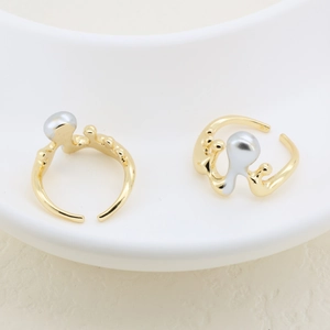 Detailed shot of irregular gold rings with silver pearls on a white ceramic plate