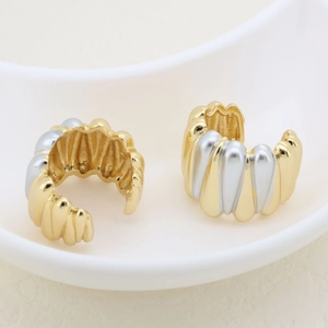 Detail of two-tone gold and silver ear cuff with wavy texture and C-shape design