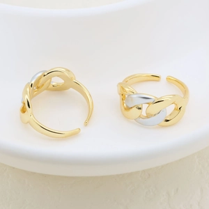 Detail of adjustable chain-link rings in gold and silver finish on white ceramic plate