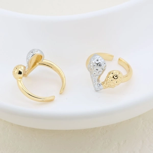 Detail of minimalist two-tone irregular open rings with hammered texture on a ceramic tray
