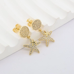Detailaufnahme der Seestern-Ohrringe aus Gold mit Zirkonia auf weißem Steinhintergrund