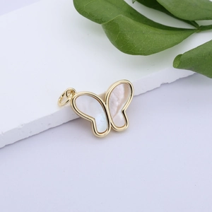 Macro detail of gold-plated butterfly pendant with white shell wings on white stone