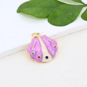 Macro shot of seashell pendant with purple enamel and colorful stones on a stone surface