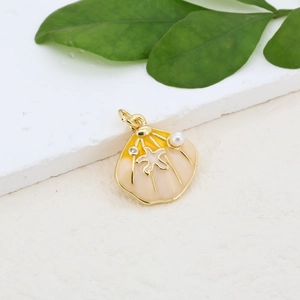 Macro shot of seashell pendant with gold starfish, pearl detail and enamel finish