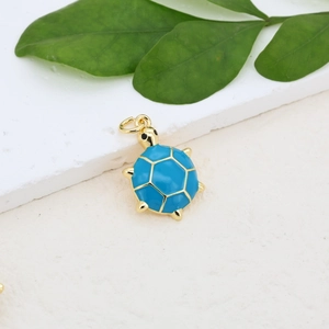 Detailed macro view of a gold-plated sea turtle pendant with vibrant blue enamel inlay