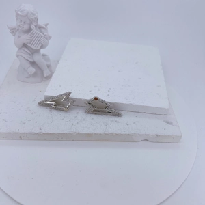Modern silver lightning bolt stud earrings with cubic zirconia on white textured stone