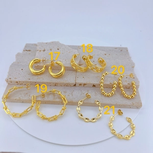 Five styles of gold-plated geometric earrings displayed on a minimalist stone plate