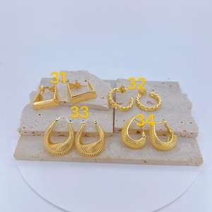 Macro view of four assorted gold-plated copper geometric earrings on stone surface