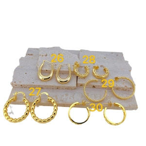 Five styles of minimalist gold plated copper geometric hoop earrings on a stone display