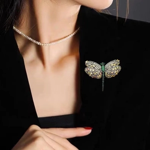 Detailed view of luxury dragonfly brooch with colorful stones on a black blazer lapel