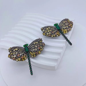 Luxury dragonfly brooches with amber and green gemstones on white textured background