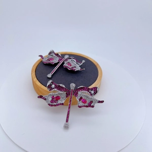 Broche libellule scintillante avec zircons rouges et blancs sur plateau en bois