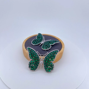Luxurious butterfly brooch set with green zircons and white stones on silver metal