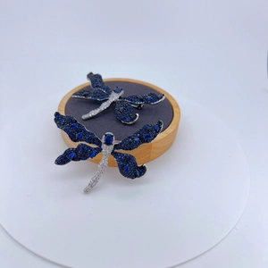 Exquisite silver dragonfly brooch set with blue crystals and white zircons on wood stand