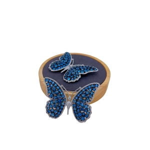 Luxury butterfly brooch set with blue crystals and silver base on wooden pedestals