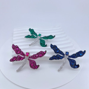 Three colors of dragonfly brooches with zircon crystals displayed on white stands