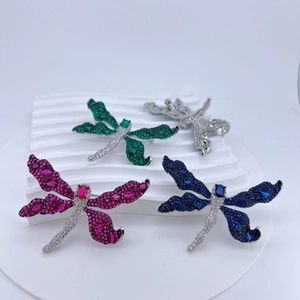 Detail view of multicolored dragonfly brooches with zircon stones on display stand