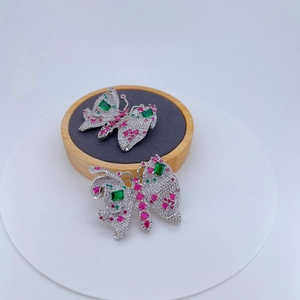 Broche papillon élégante avec zircons et pierres vert émeraude sur un socle gris doux