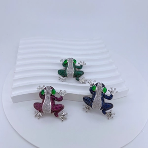 Detailed macro view of green, purple, and blue cubic zirconia frog brooches with pavé stones