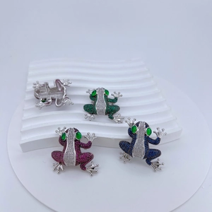 Macro detail of frog brooches with micro-inlaid colorful zircons on white display