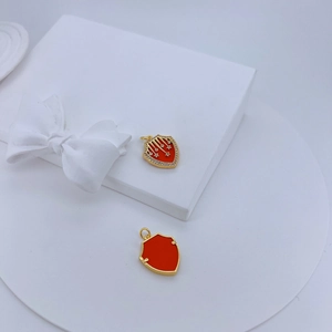 Detail of shield-shaped gold pendants with star engraving and orange enamel finish