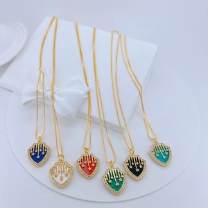 Detail of 18K gold plated shield pendants with zircon inlay and multi-color stone centers
