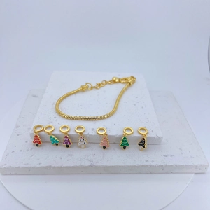 Detail of gold snake chain bracelet with seven colorful Christmas tree charms on stone base