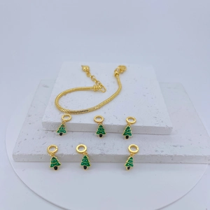 Golden snake chain bracelet with green enamel Christmas tree charms on a white stone base