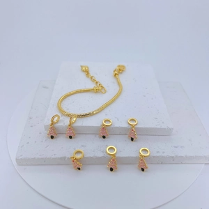 Detailed macro view of gold snake chain bracelet with pink enamel Christmas tree charms